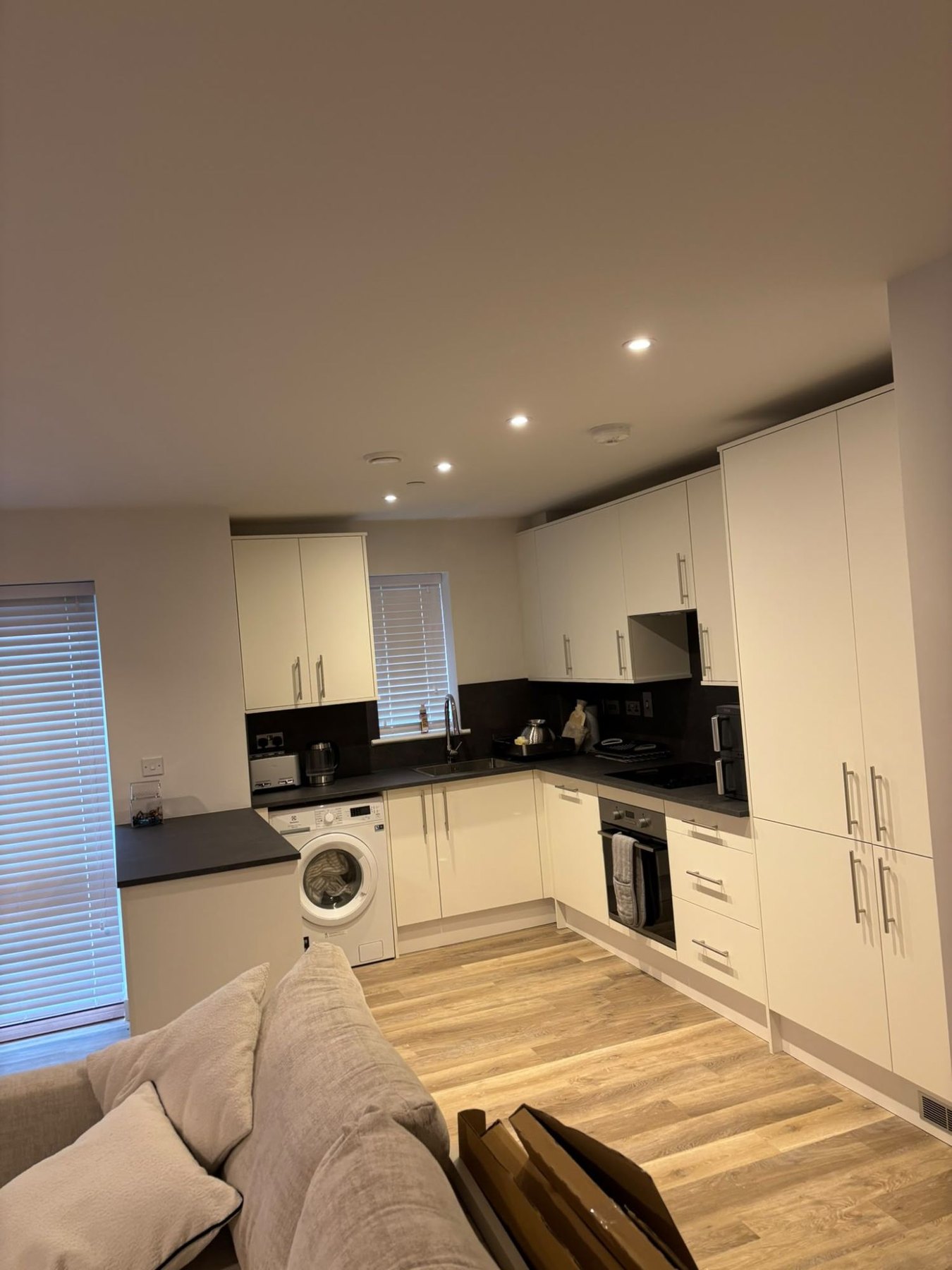 Cream fitted kitchen with a washing machine housed in the run and full-height storage alongside